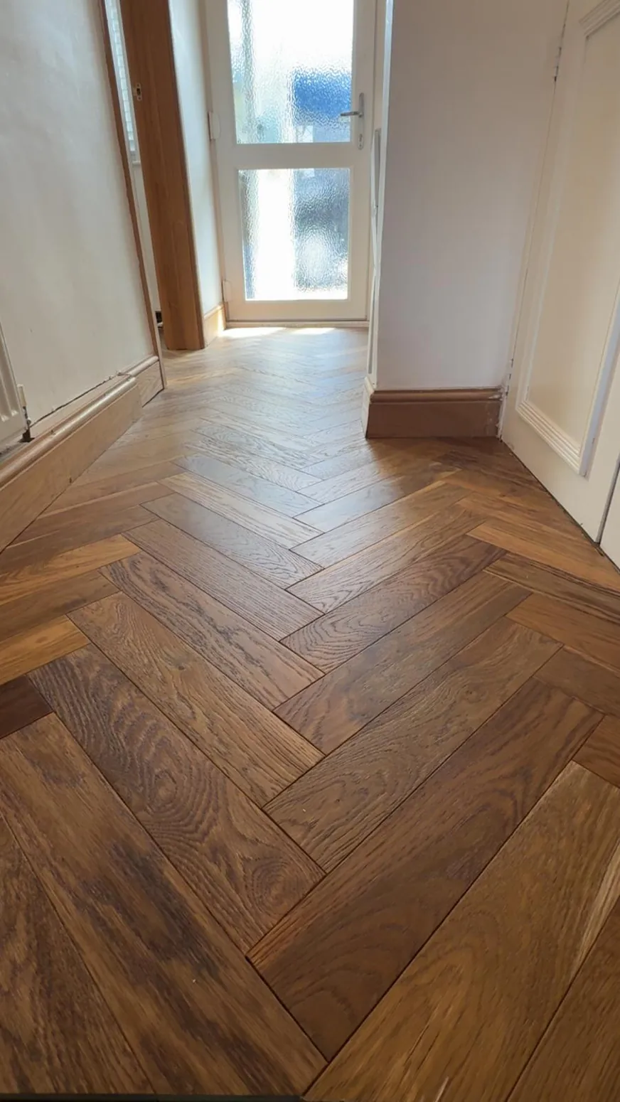 Neatly laid herringbone wood-effect flooring